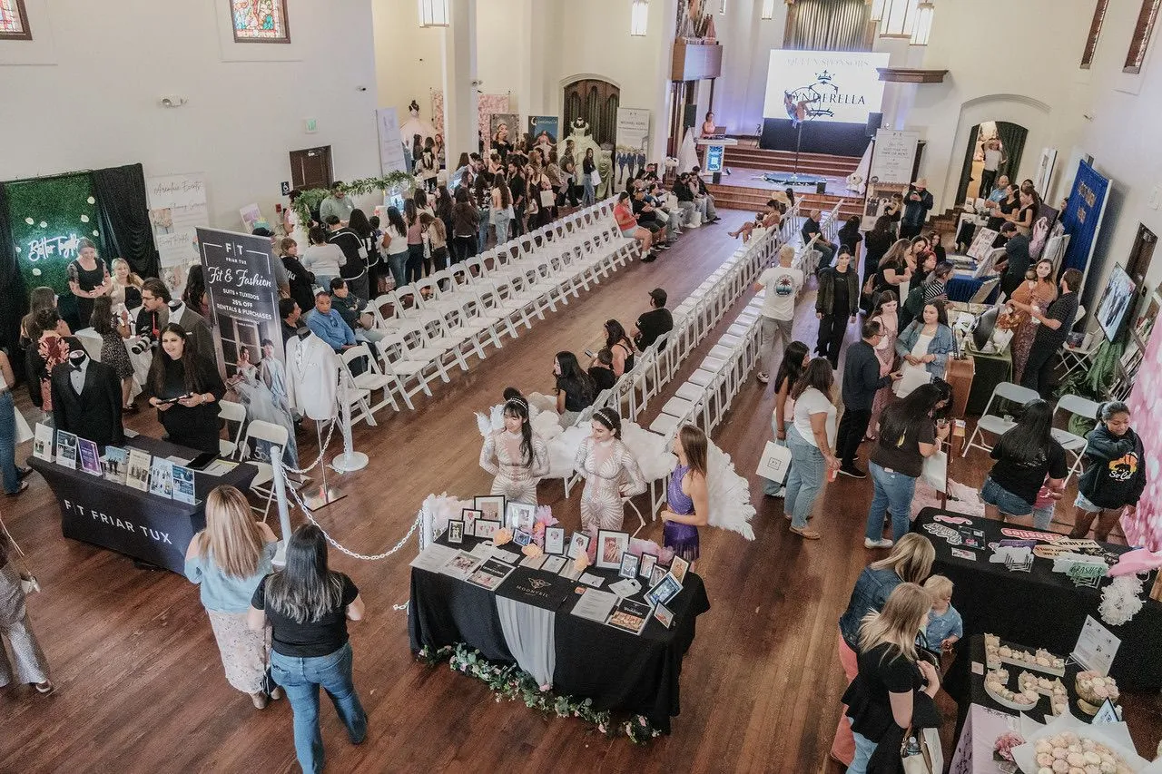 Busy trade show and expo floor with vendor booths, guests, and a presentation stage